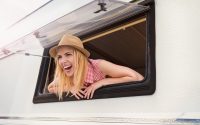Beautiful young woman in a camper van on a summer day